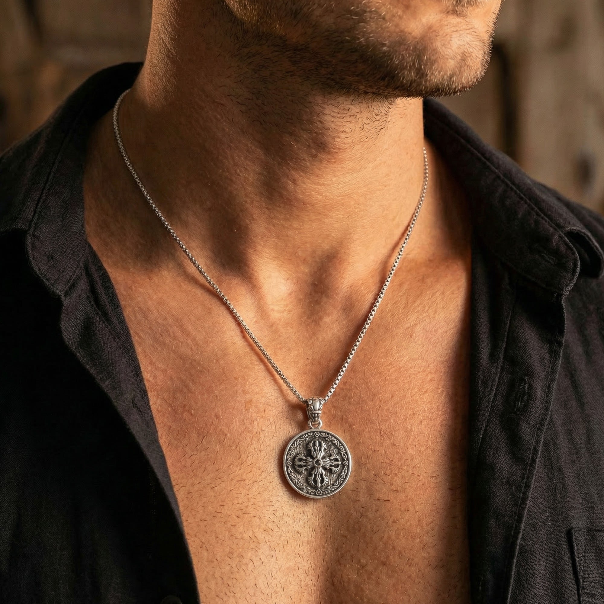 Close-up of young man in open-neck shirt wearing sterling silver men's silver Tibetan vajra cross amulet necklace.