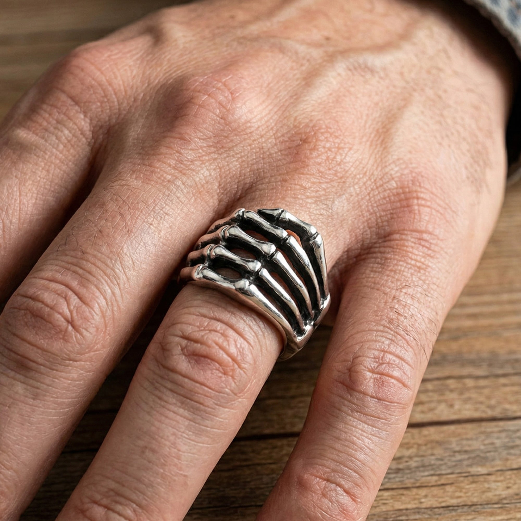 Close-up of man's hand wearing stainless steel men's skeleton hand ring.