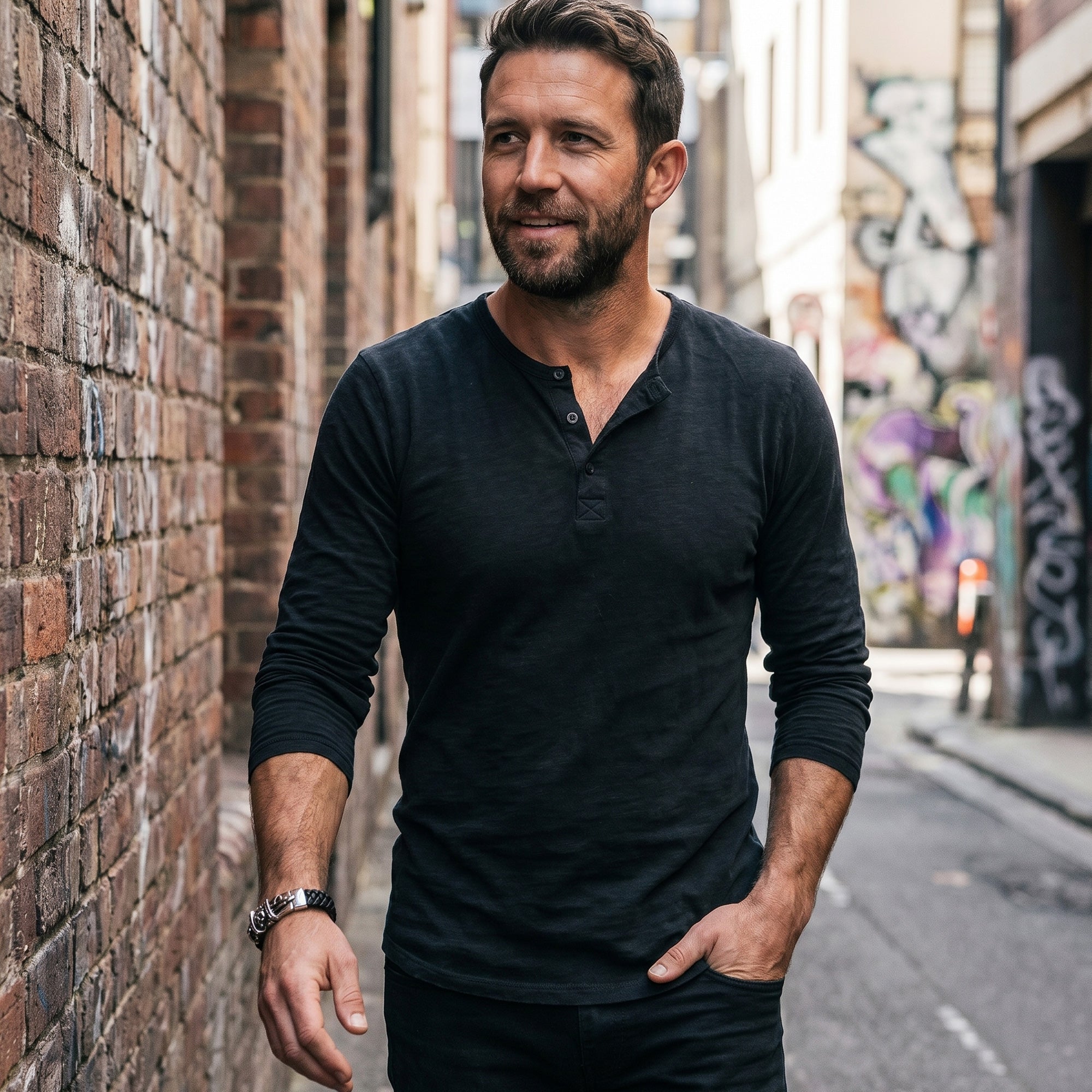 Man walking in a narrow alleyway wearing a Save Brave skull & dagger men's leather bracelet.