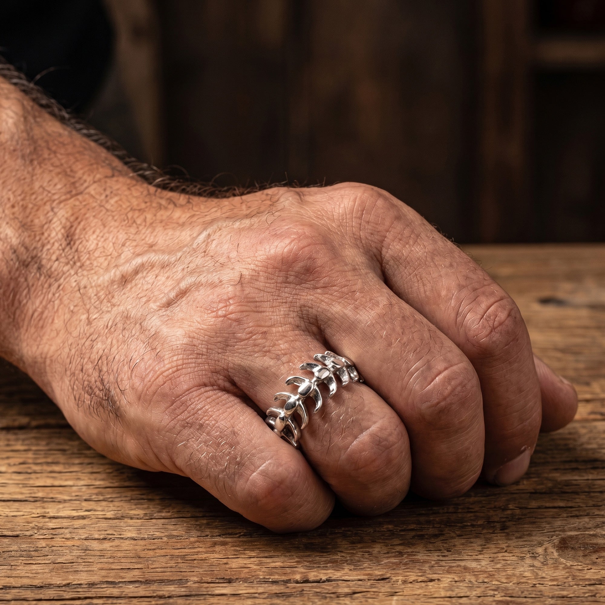 Close-up of a man's hand wearing a stainless steel spine vertebrae ring.