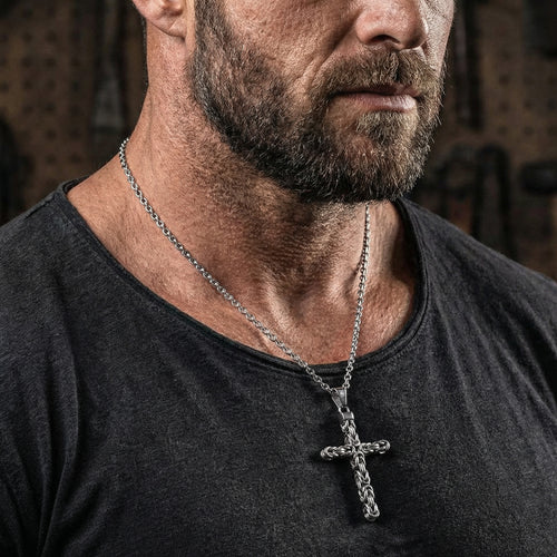 Side close-up of a rugged man wearing a stainless steel Byzantine rope knot cross necklace.