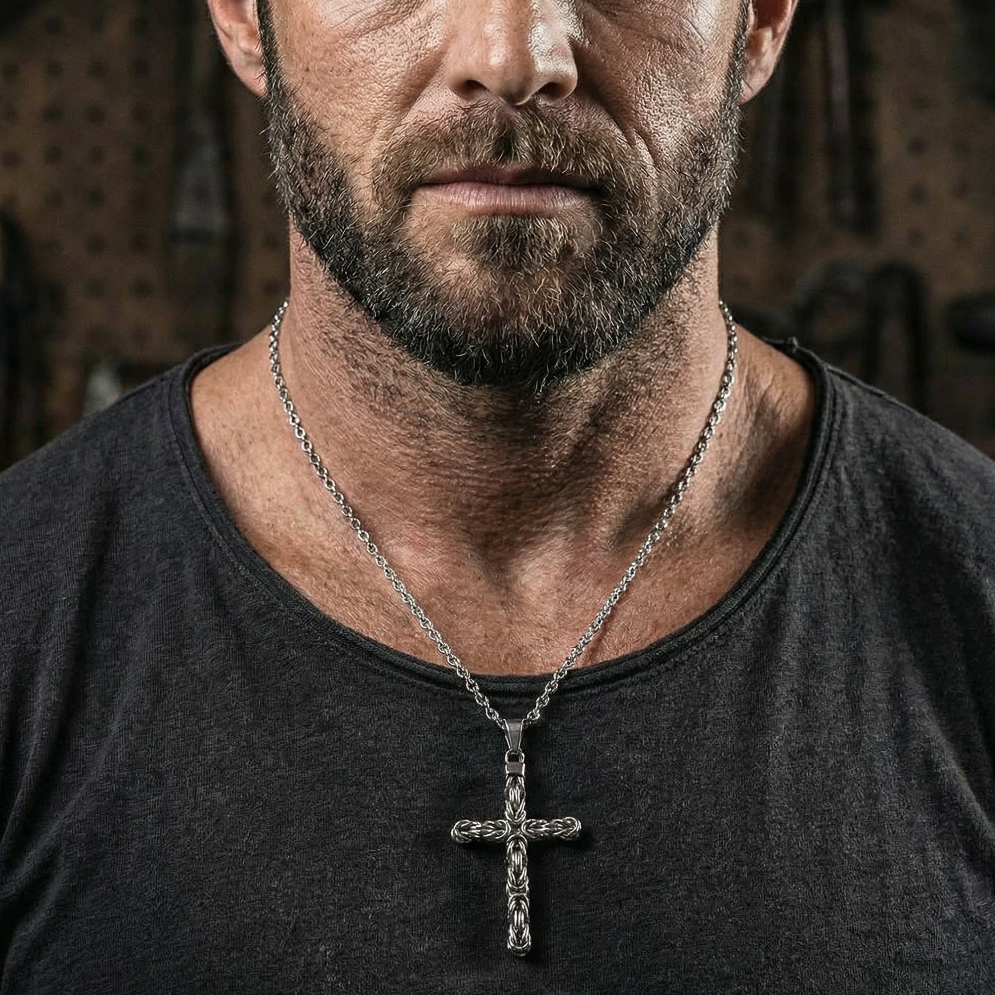 Close-up of a rugged man wearing a stainless steel Byzantine rope knot cross necklace.