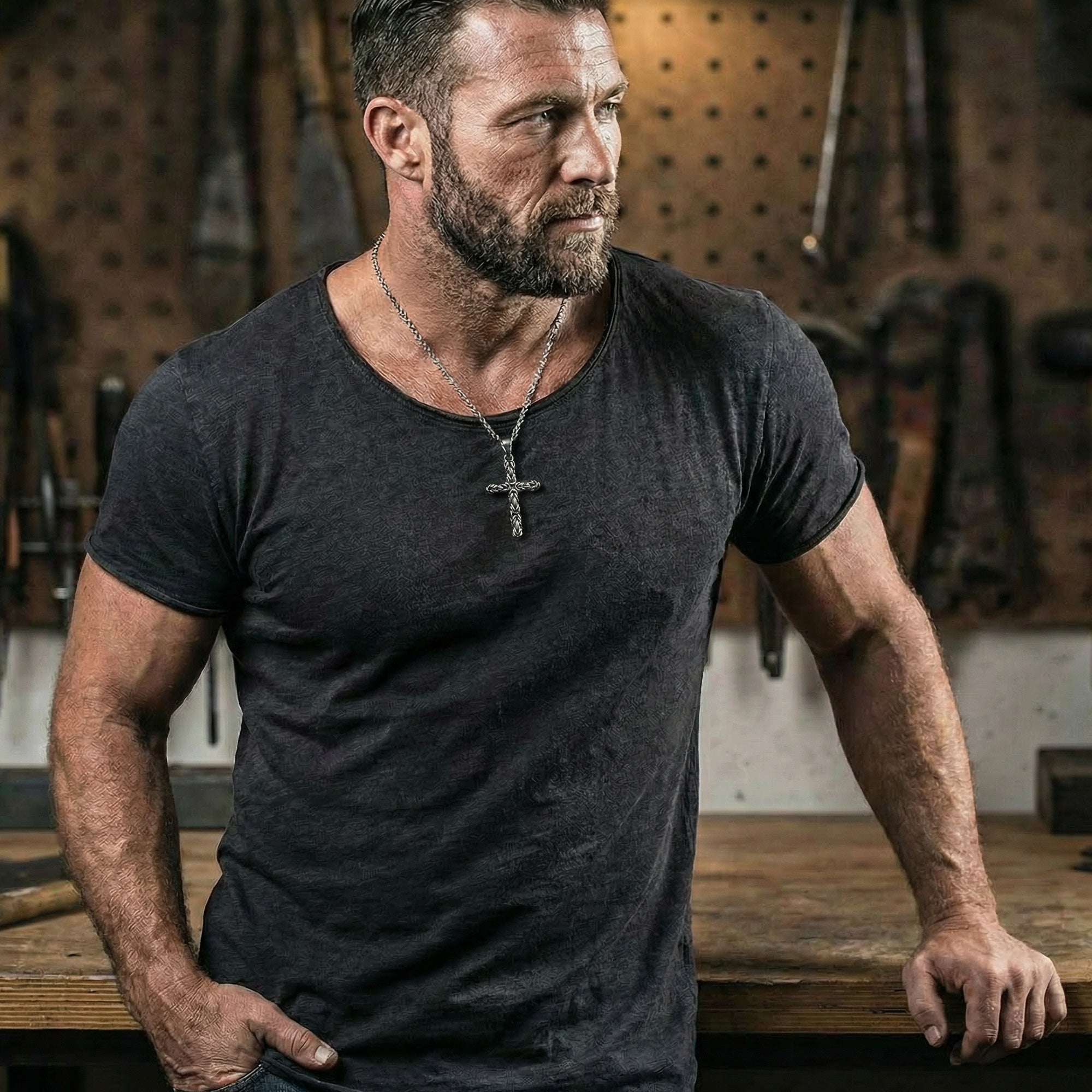 Man wearing a stainless steel Byzantine rope knot cross necklace standing next to a workshop bench.