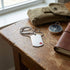 Medical alert stainless steel matt finish dog tag necklace on a wooden table with a compass and journal.