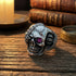 Stainless steel men's skull eye patch ring sitting on an old wooden table.
