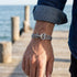 Man standing on jetty wearing Anchor & Crew Admiral sterling silver grey rope bracelet.