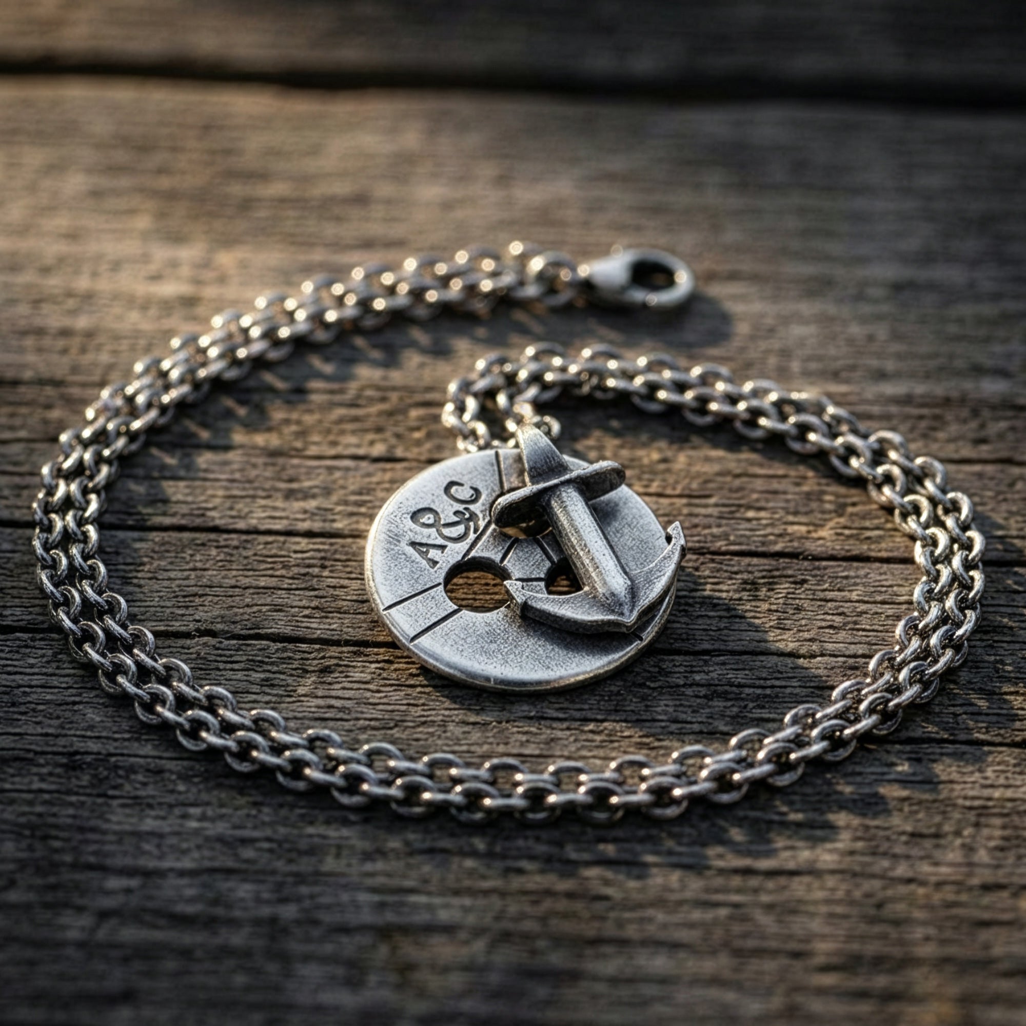 An Anchor & Crew Lerwick pulley and anchor sterling silver necklace on a wooden deck.