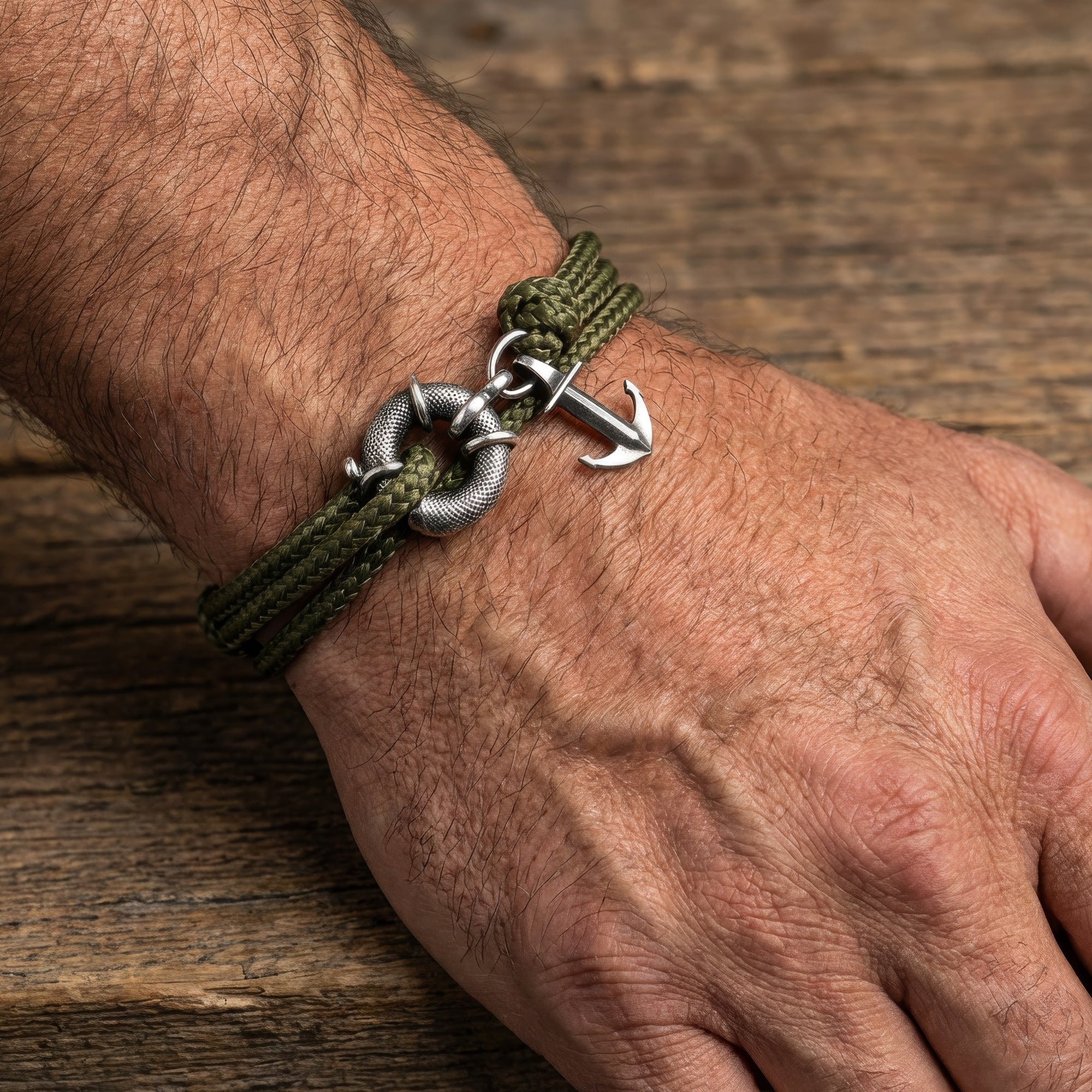 Close up of man wrist wearing Anchor & Crew Clyde sterling silver khaki green rope bracelet.