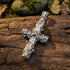 Sterling silver lashed wood cross necklace laying on a log outdoors.