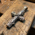 Sterling silver lashed wood cross necklace on wooden work bench.