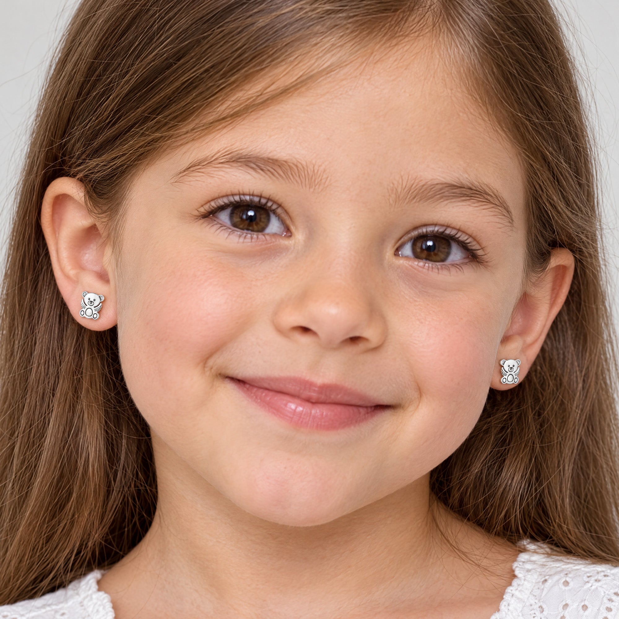 Young girl wearing Herzengel teddy bear angel wings children's earrings.