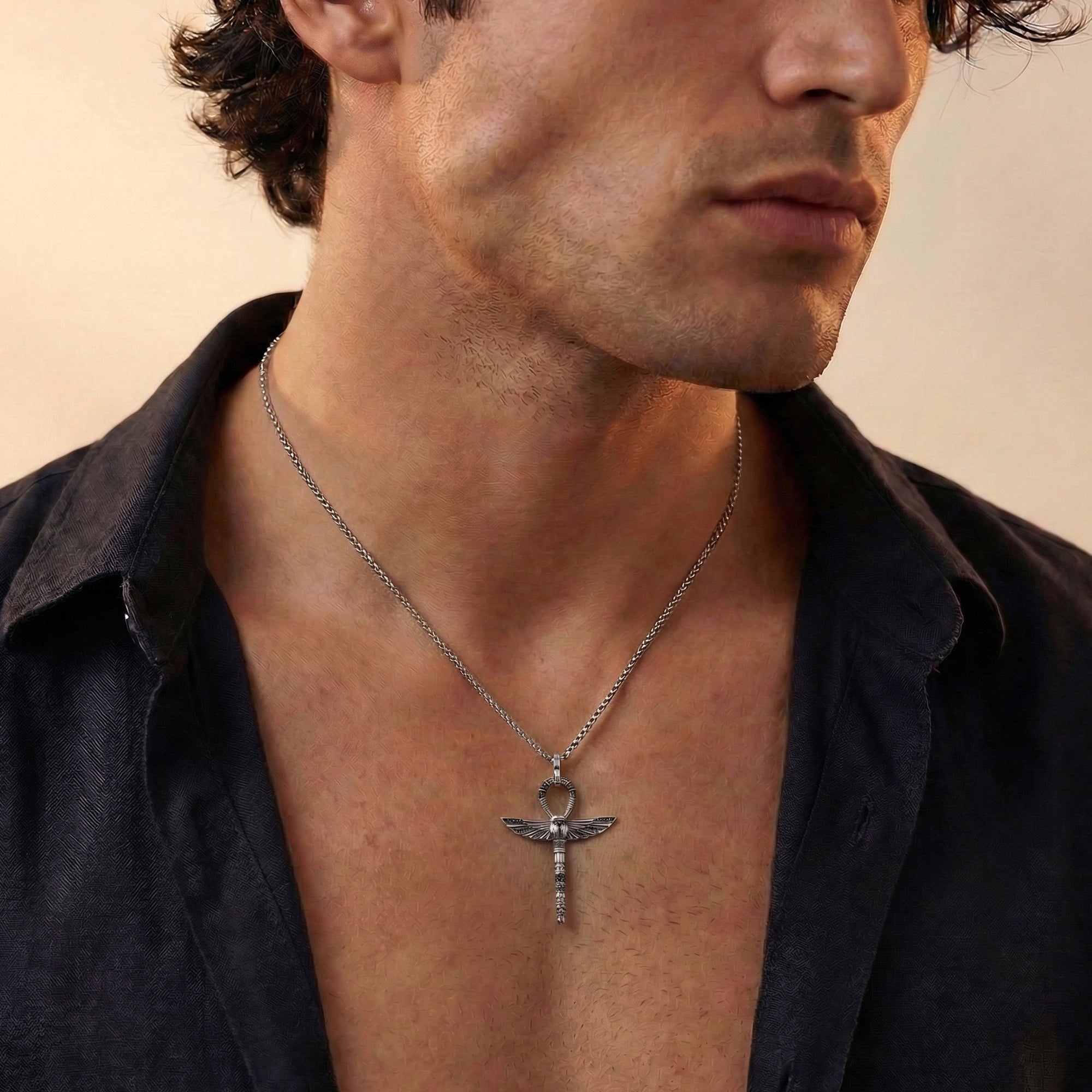 Young man in open-neck shirt wearing Thomas Sabo cross of life ankh scarab pendant.