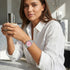 Woman holding a coffee cup while wearing a Thomas Sabo Haribo Goldbear pink dial silver watch on her wrist.