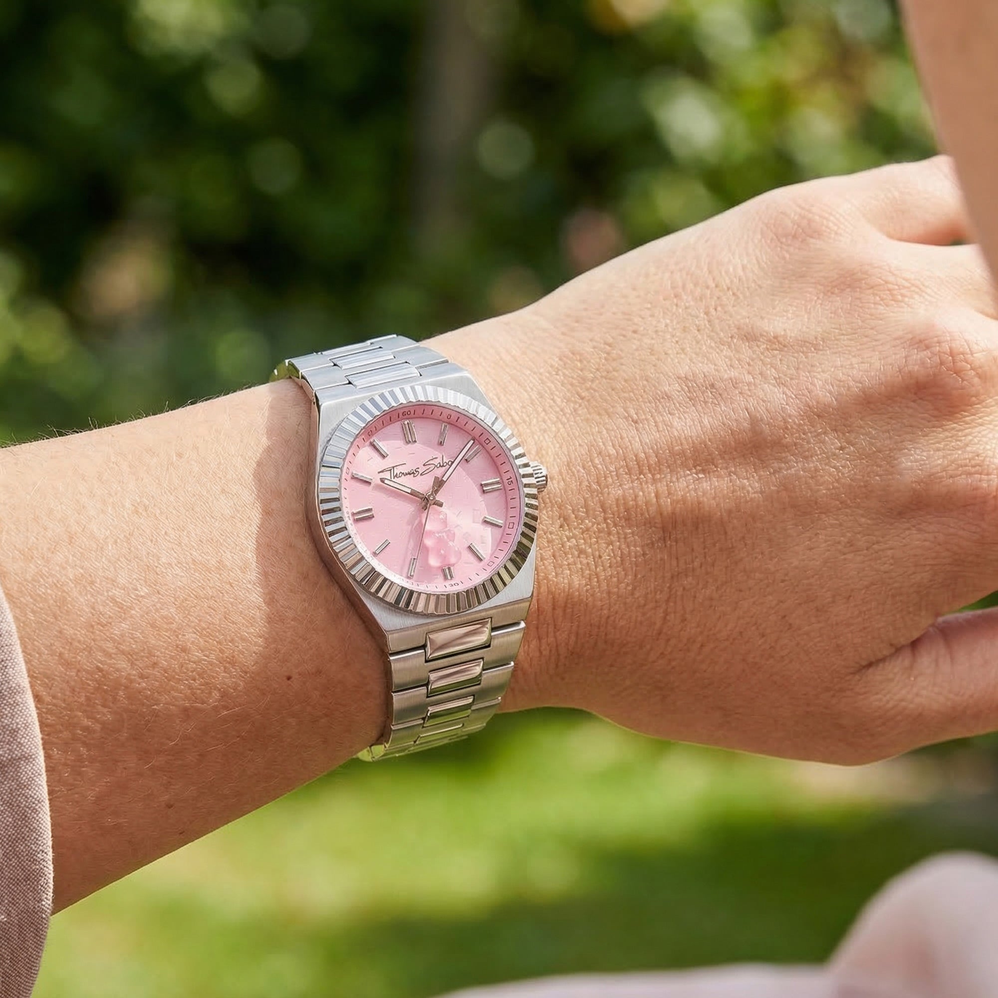 Woman wearing a Thomas Sabo Haribo Goldbear pink dial silver watch on her wrist.