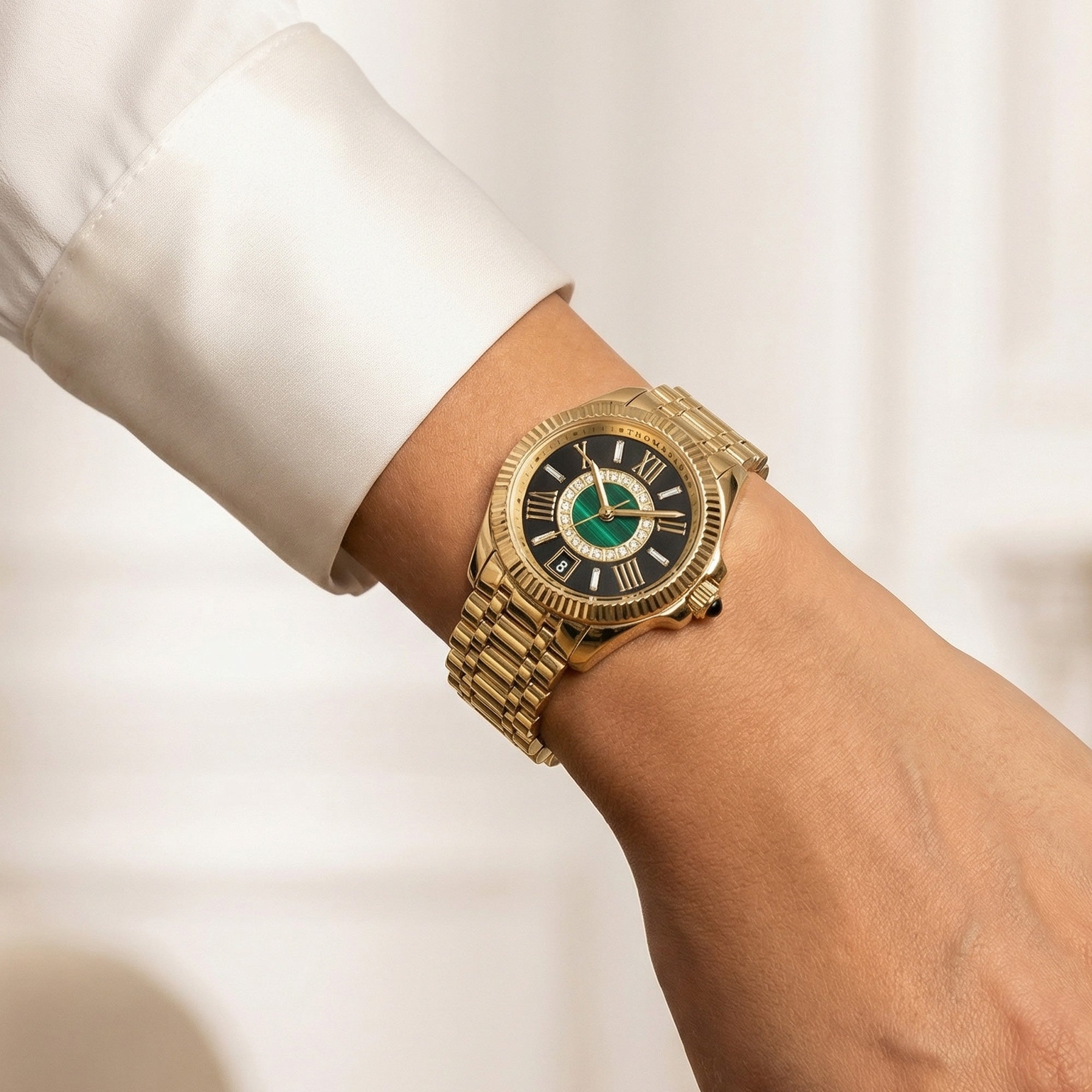 Close-up of a woman wearing a Thomas Sabo Mystic Island gold malachite watch on her wrist.