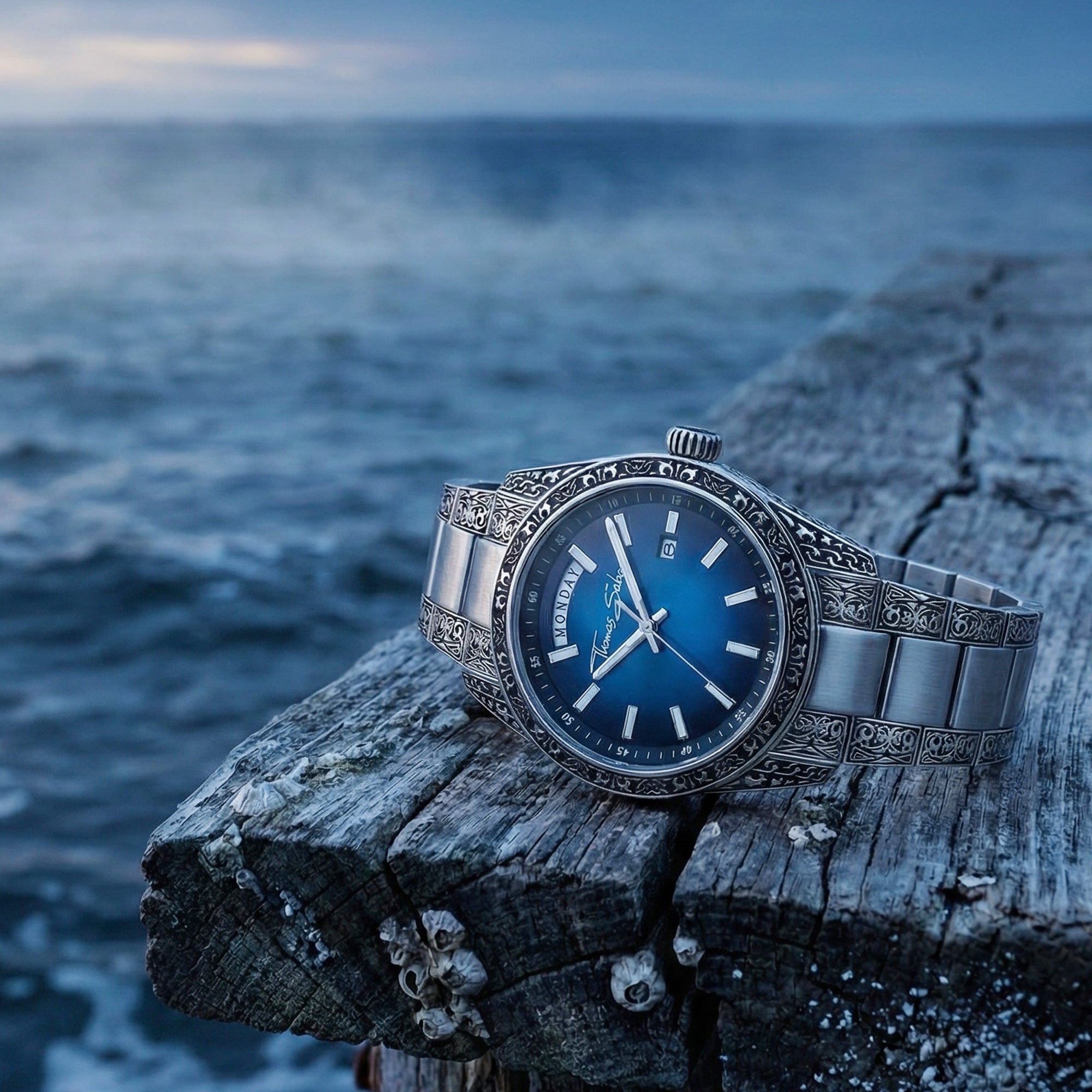 Thomas Sabo Rebel At Heart Revive 40mm blue dial watch on the edge of an old wooden pier with the sea frothing in the background.