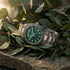 Thomas Sabo Rebel At Heart Revive 36mm green dial watch resting on a bed of eucalyptus leaves on a rough stone surface.