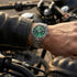 Man in a leather jacket standing next to a motorcycle wearing a Thomas Sabo Rebel At Heart Revive 36mm green dial watch.