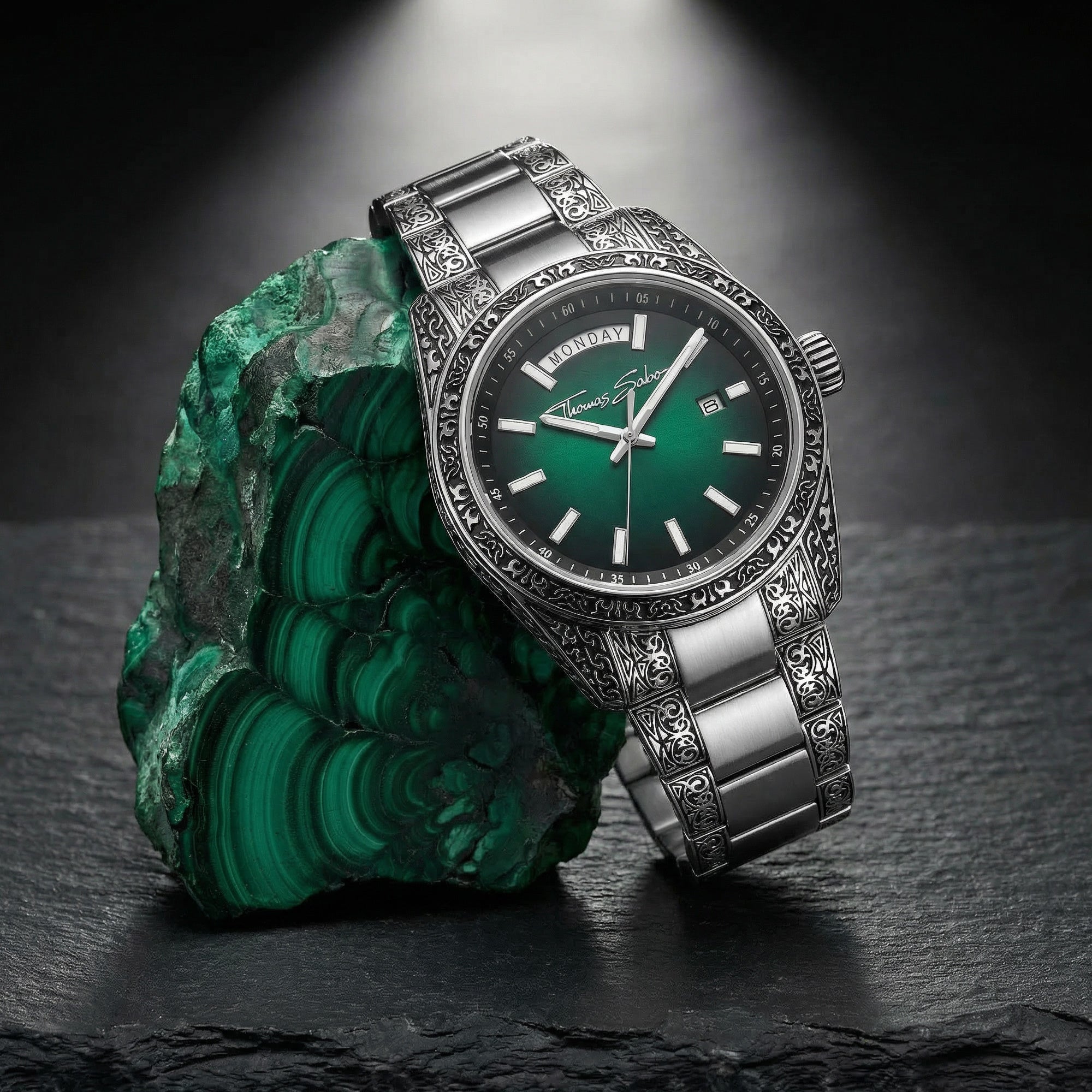 Thomas Sabo Rebel At Heart Revive 40mm green dial watch leaning against a rough piece of malachite sitting on a black slate surface.