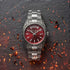 A Thomas Sabo Rebel At Heart Revive 36mm red dial watch on black slate surrounded by burning embers and sparks.