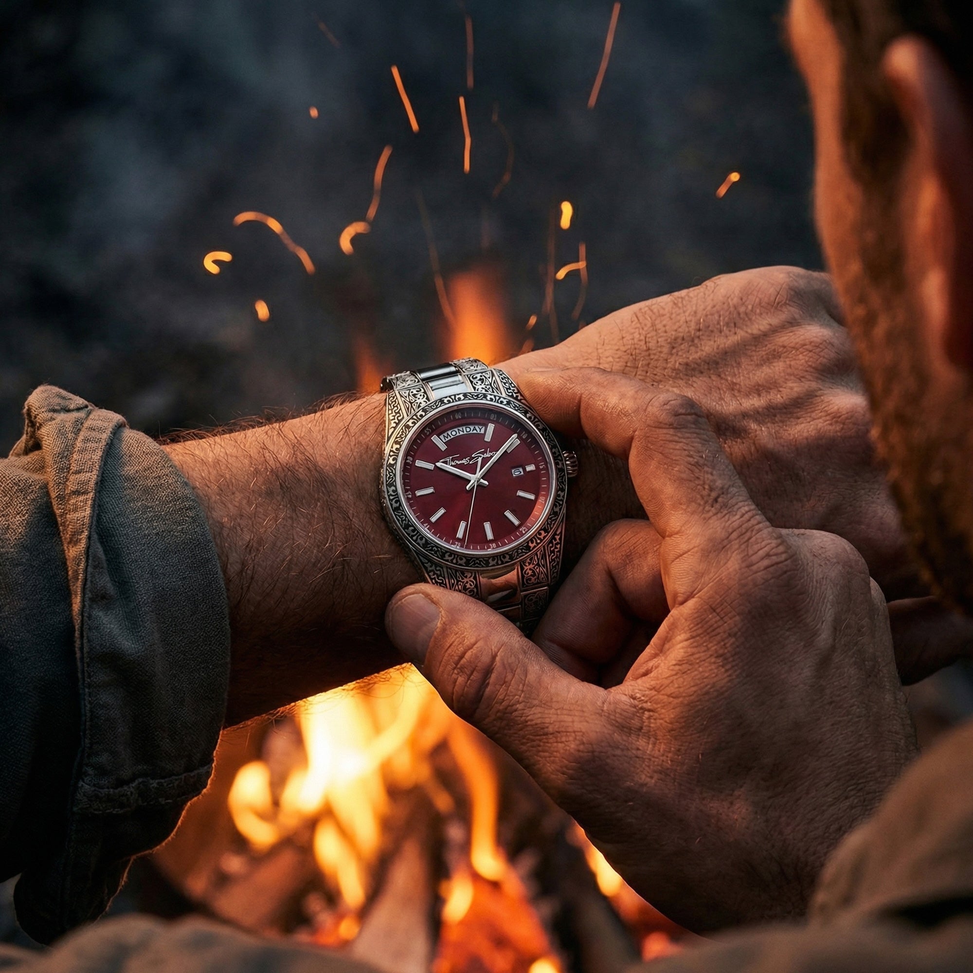 A man checks the time on his Thomas Sabo Rebel At Heart Revive 36mm red dial watch next to a campfire.