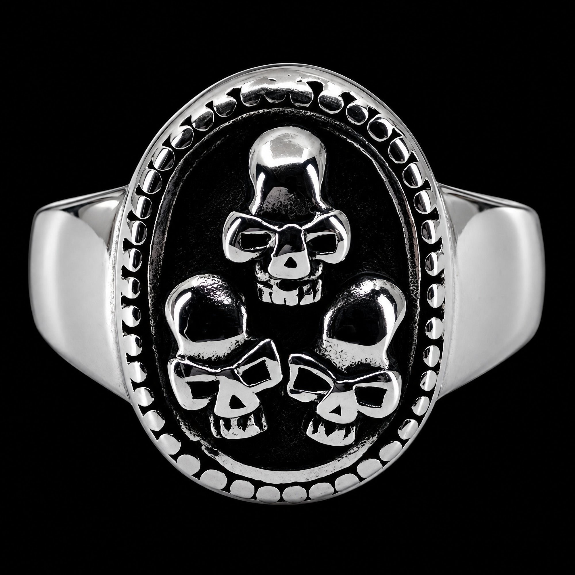 Front view of a three skulls stainless steel men's signet ring.