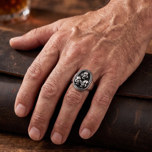 Man wearing a three skulls stainless steel signet ring.