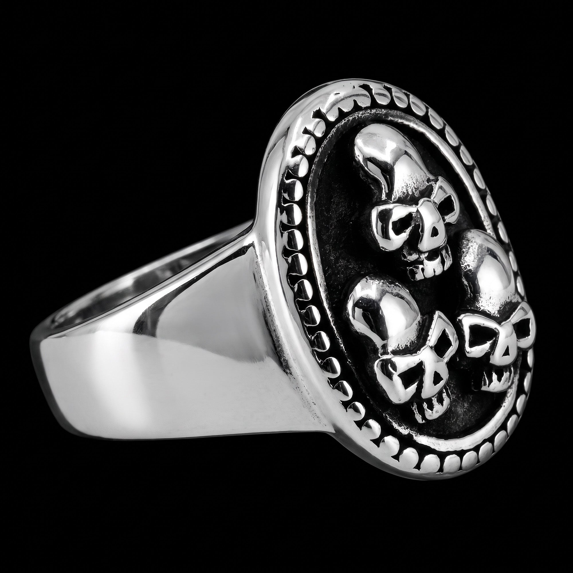 Side view of a three skulls stainless steel men's signet ring.