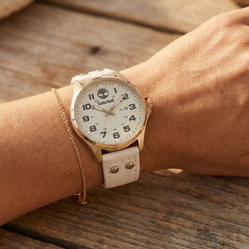 Woman wearing Timberland Alstead gold sand dial leather strap watch.