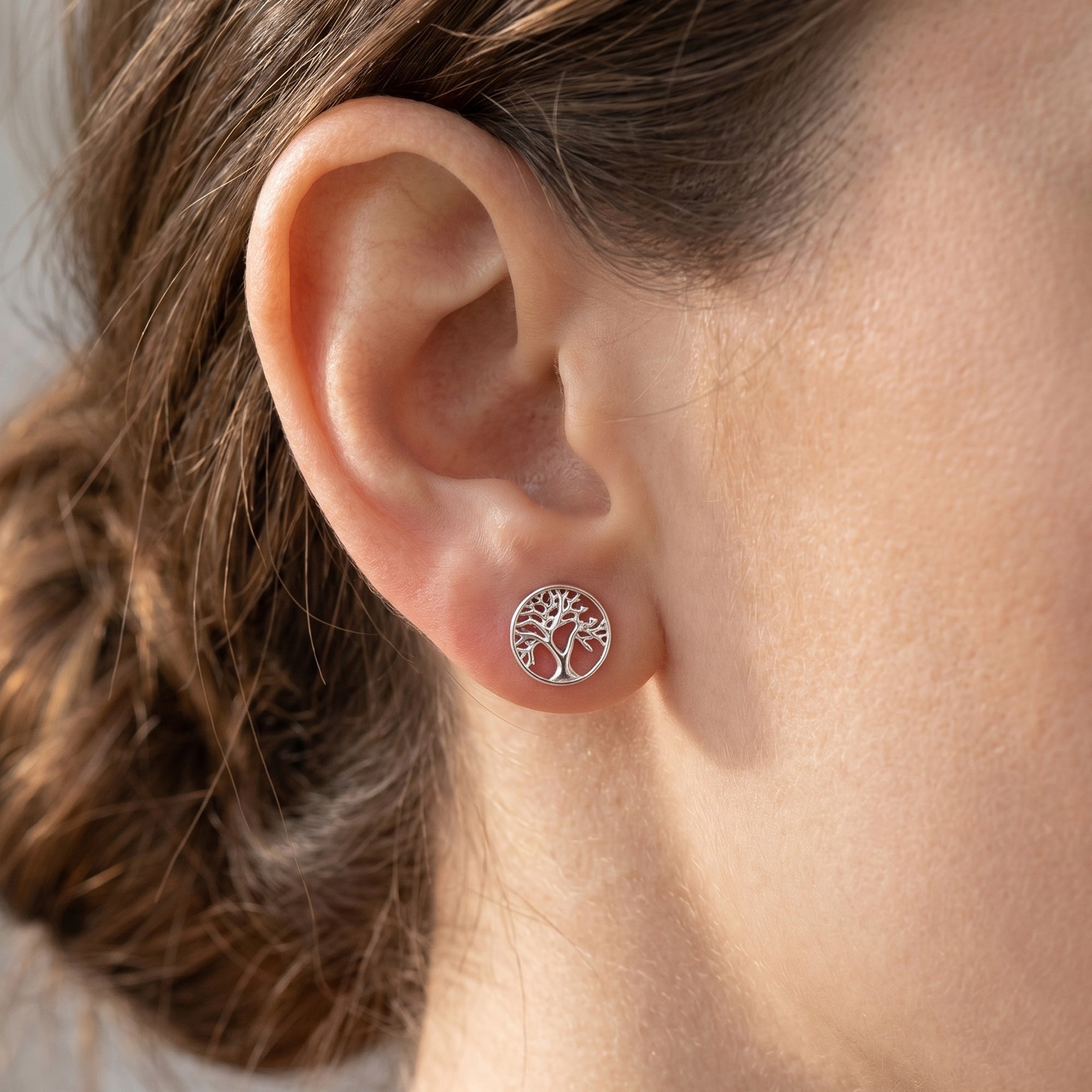 Woman wearing Engelsrufer tree of life mini circle silver earrings.