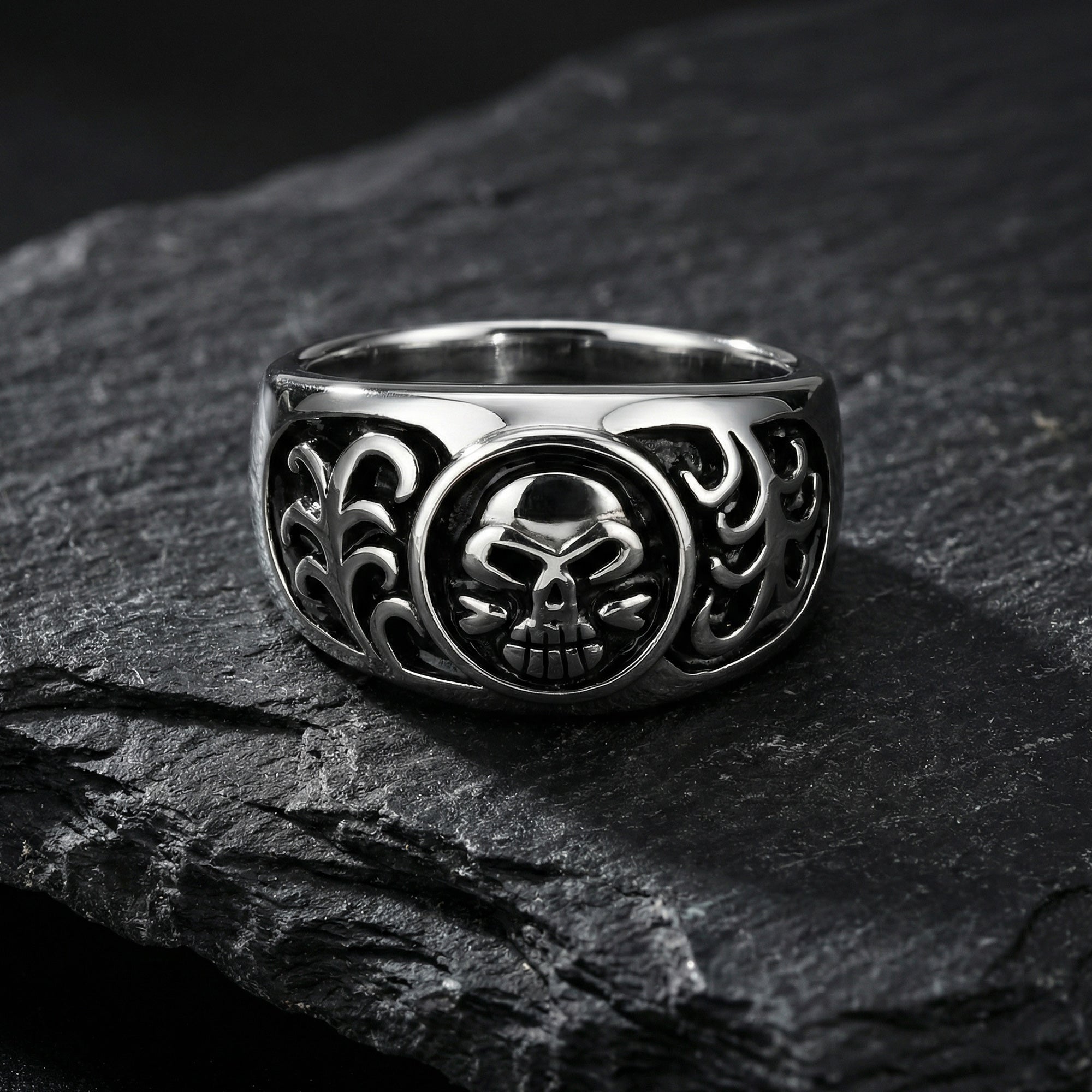 Men's tribal skull stainless steel ring on a black shale stone surface.