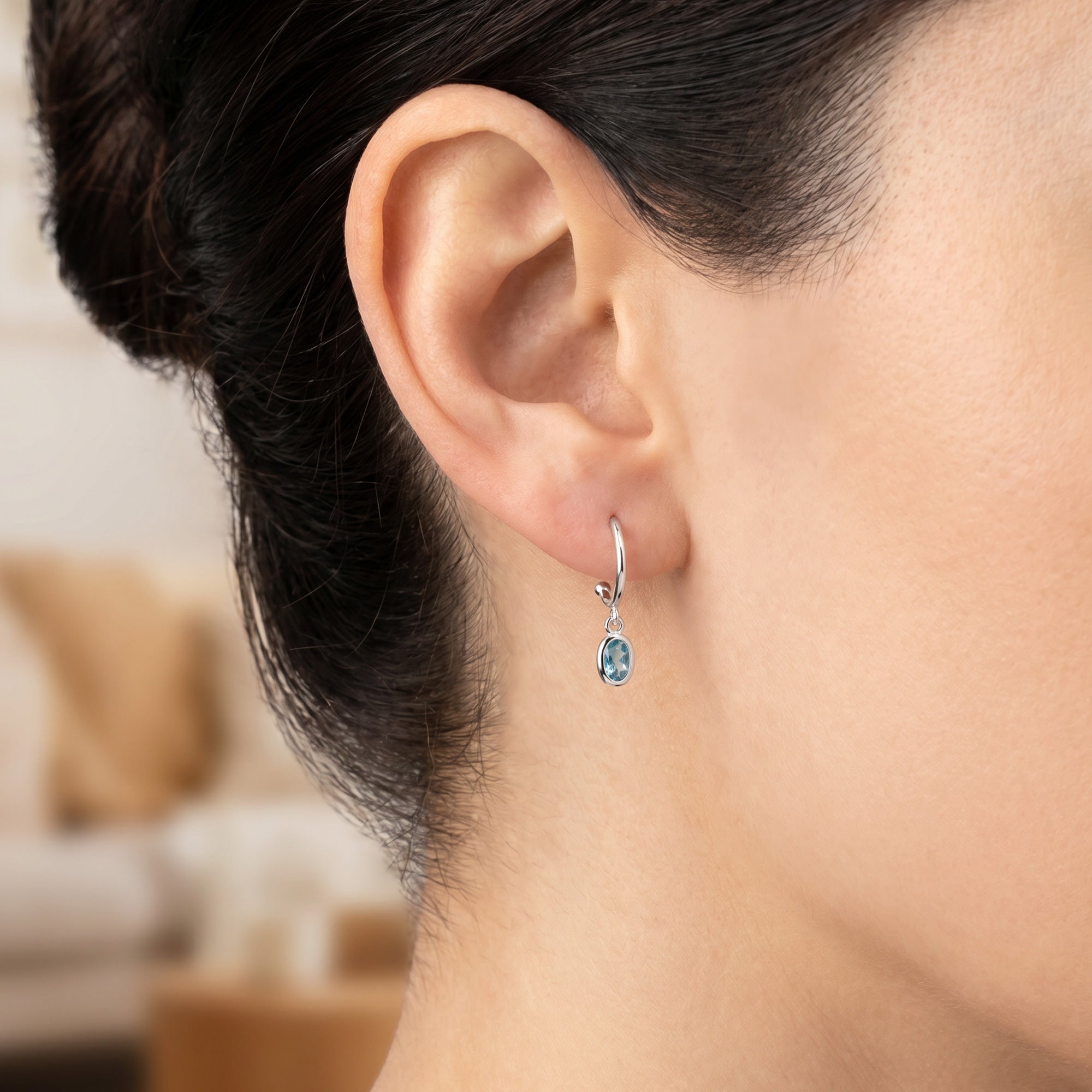 Close-up of woman wearing Engelsrufer turquoise blue CZ hoop dangle earrings.