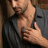 Man in open-neck shirt wearing sterling silver men's silver Tibetan vajra cross amulet necklace.