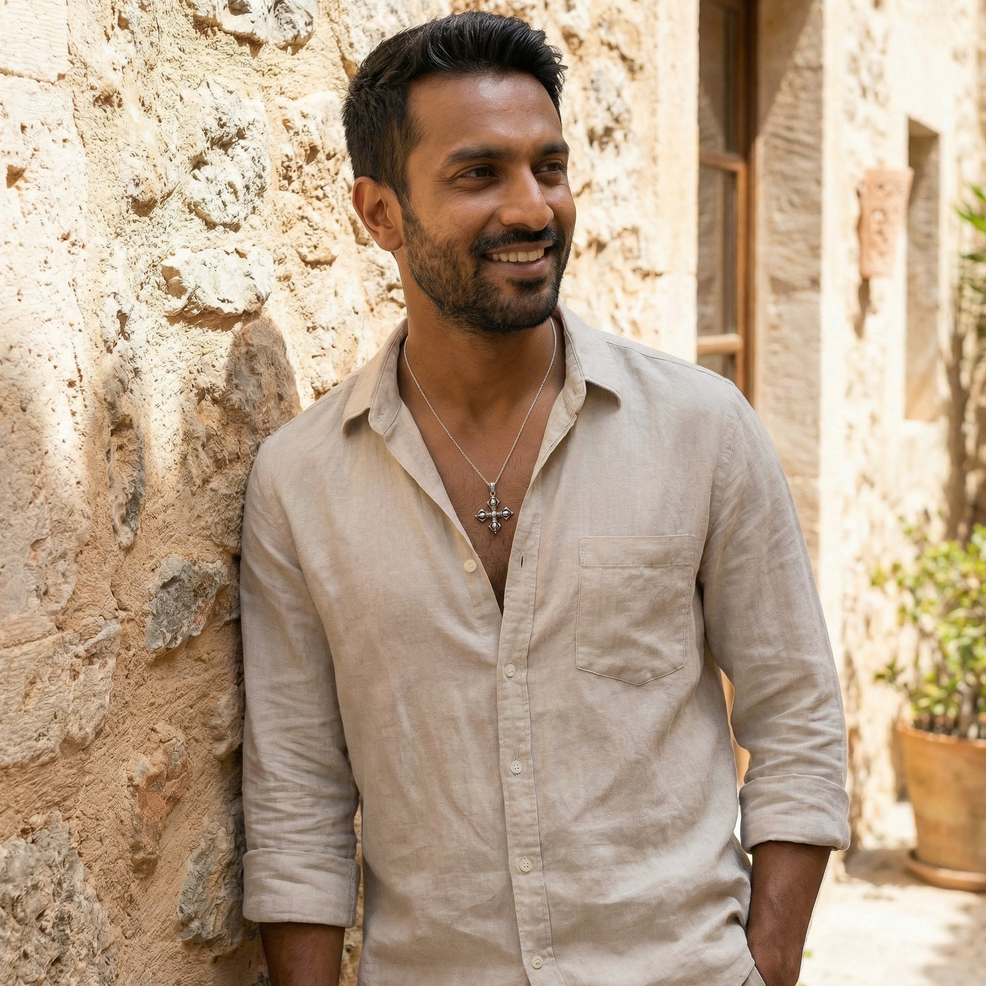 Young man in a calico open-neck shirt wearing a vajra cross sterling silver necklace.