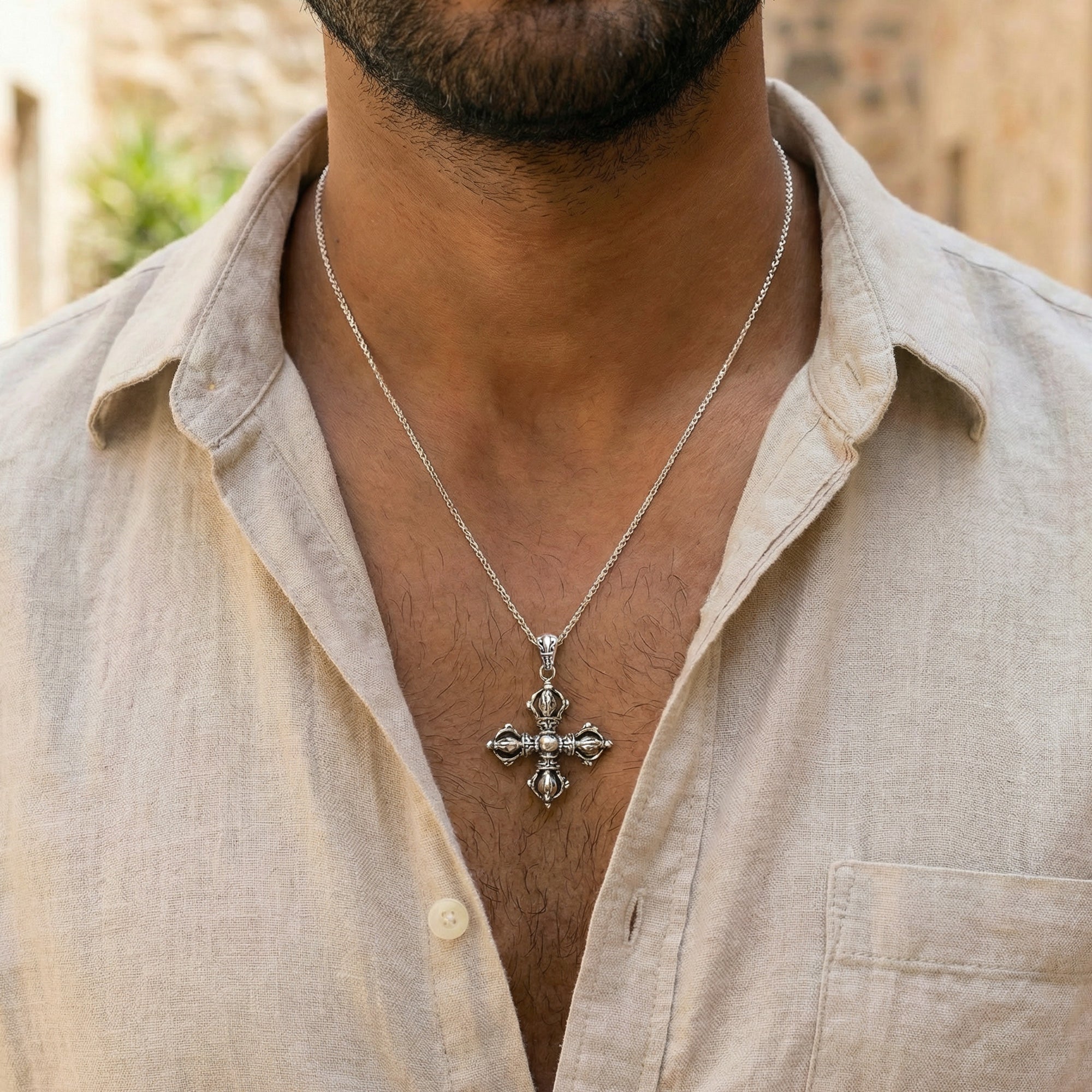 Close up of a young man in a calico open-neck shirt wearing a vajra cross sterling silver necklace.