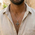 Close up of a young man in a calico open-neck shirt wearing a vajra cross sterling silver necklace.