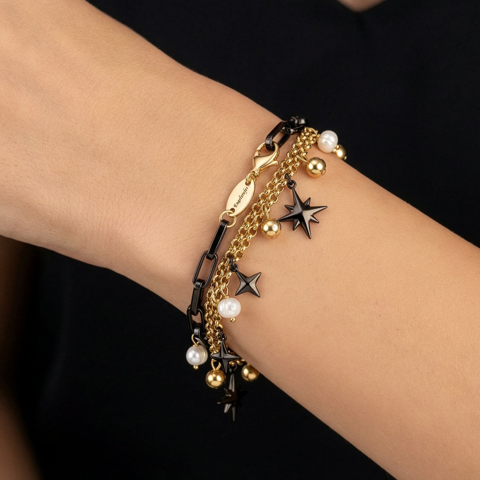 Close-up of a woman's wrist wearing an Engelsrufer wind rose gold and black boho pearl bracelet.