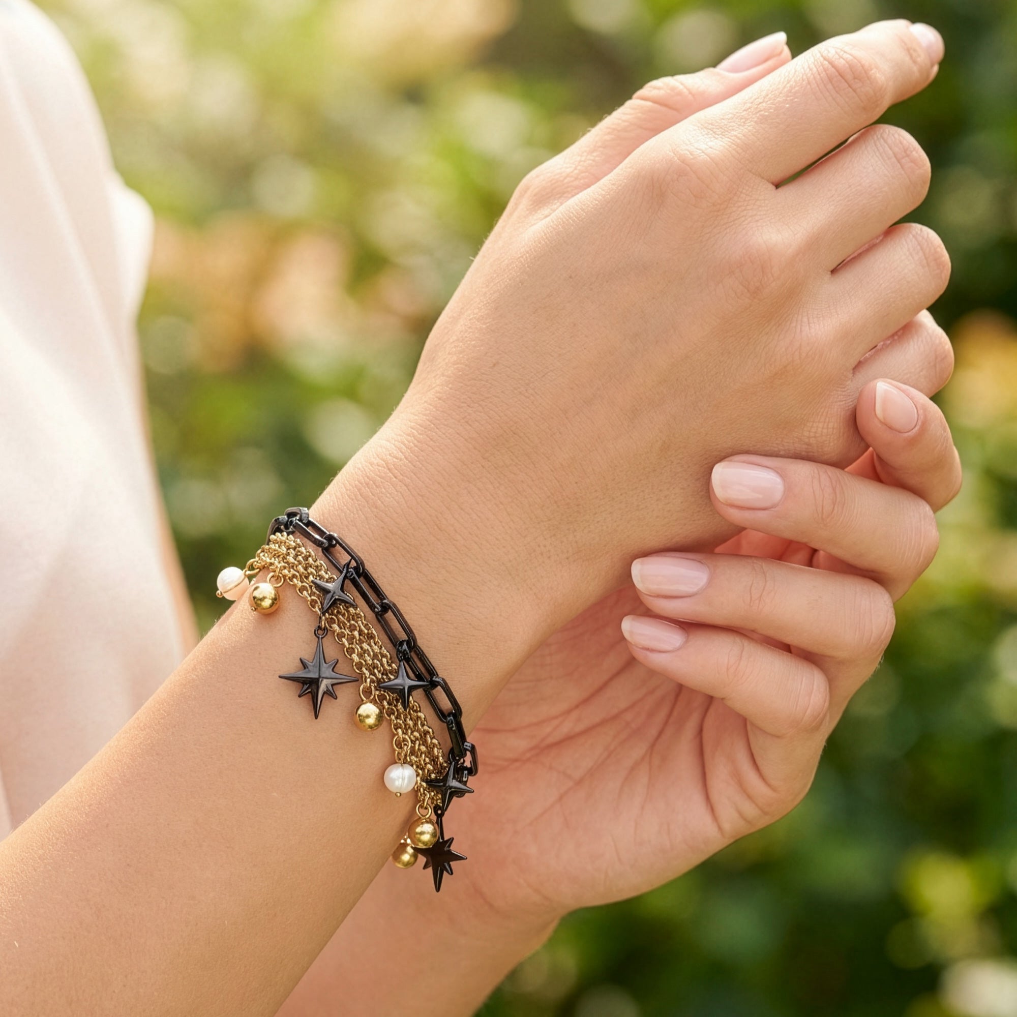 Close-up of a woman wearing an Engelsrufer wind rose gold and black boho pearl bracelet.