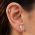 Close-up of woman wearing Engelsrufer angel wings silver rose gold mismatch stud earrings.